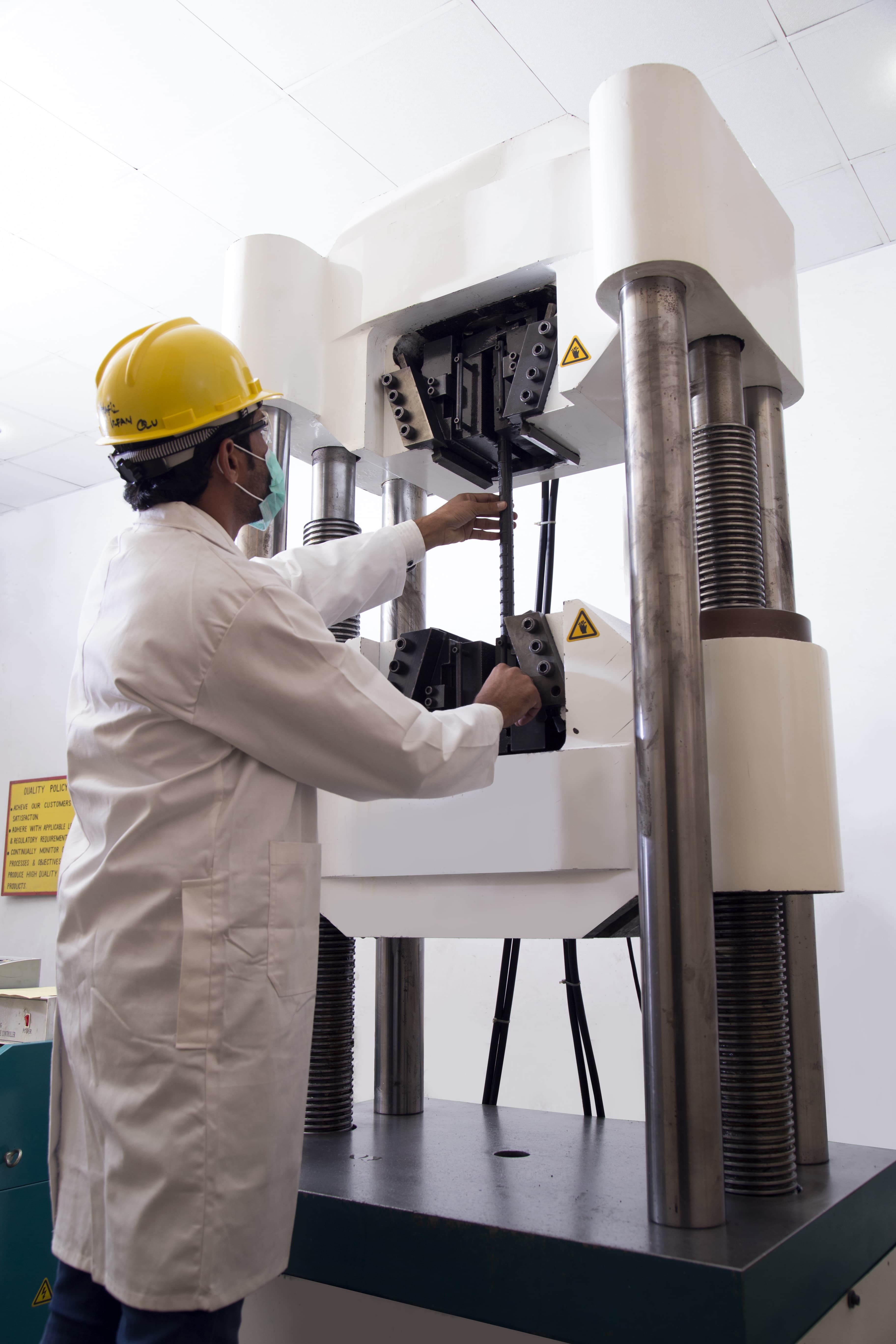 Technician loading a rebar sample into the Universal Testing Machine at AFCO Steel